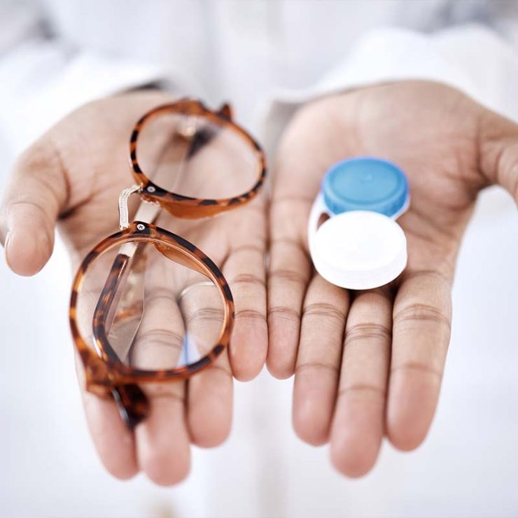 Optometrist showing a contact lens container and glasses frame in tortoise.