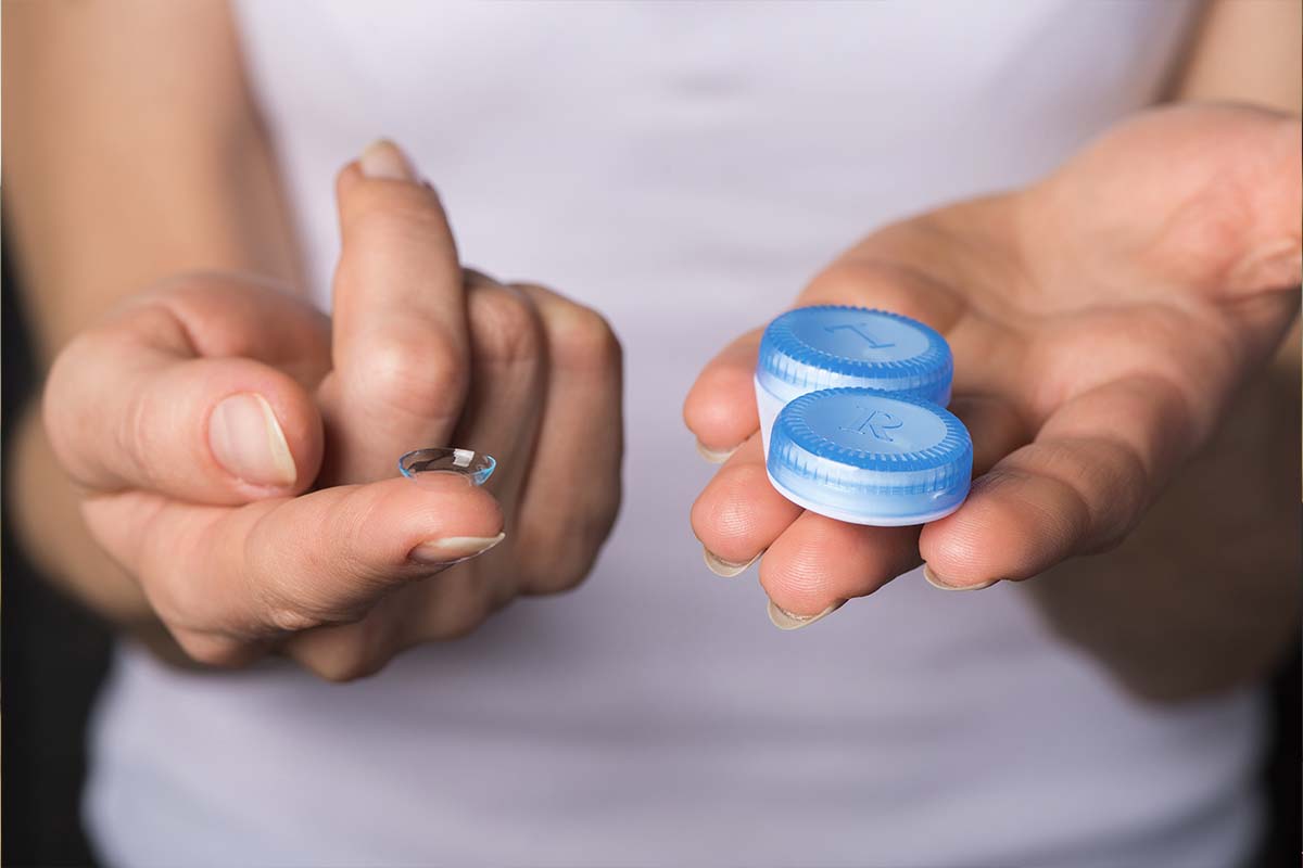 Hands showing contact lens and the container.